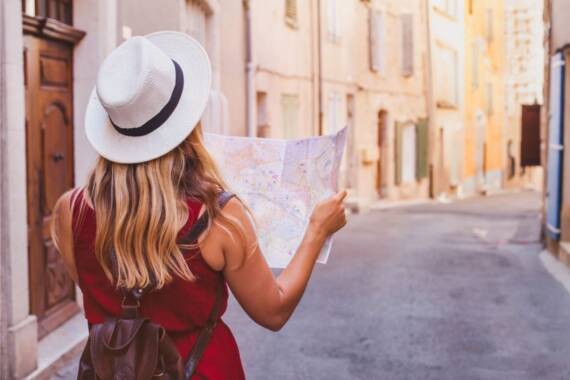 verão europeu eventos de verão eventos de verão Na foto, uma mulher de chapéu olhando um mapa em uma rua na Europa