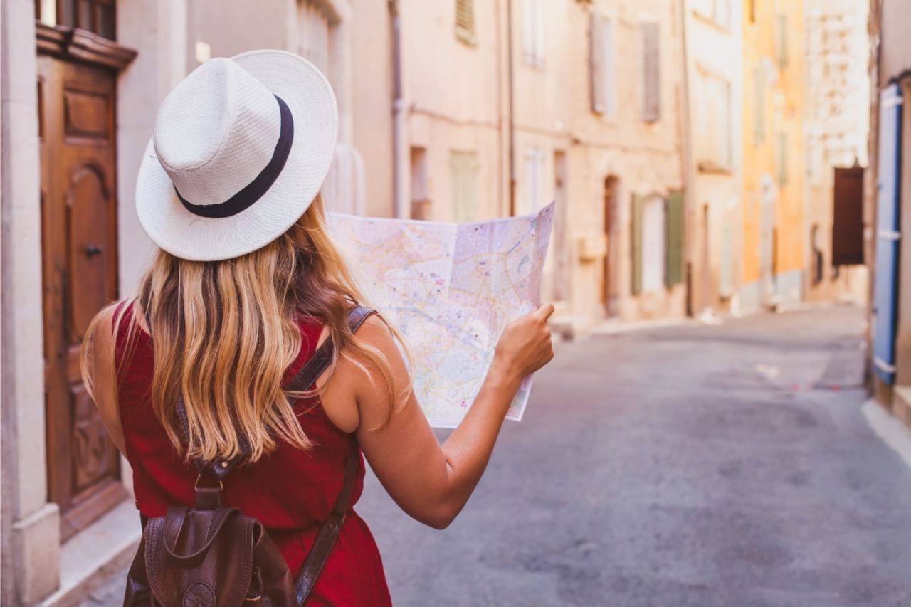 verão europeu eventos de verão eventos de verão Na foto, uma mulher de chapéu olhando um mapa em uma rua na Europa