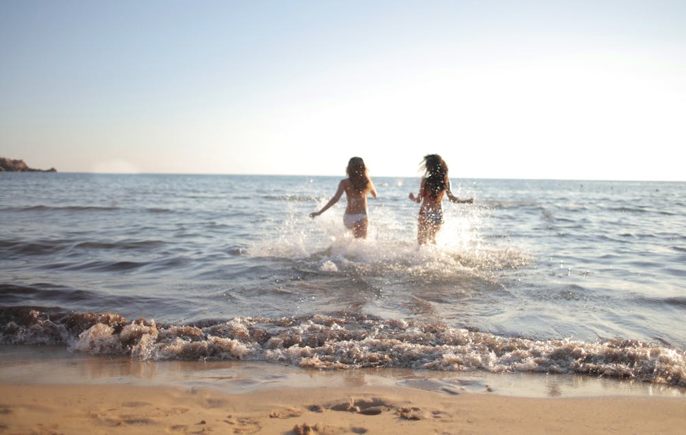 duas mulheres tomando banho em praia de água quente no litoral brasileiro.