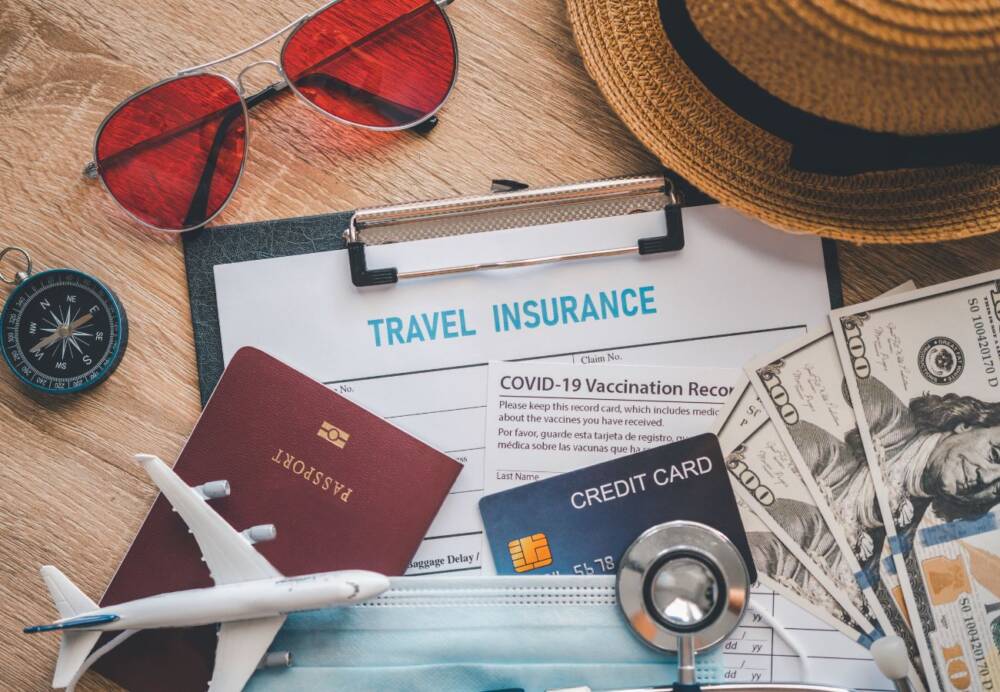 Imagem com objetos de viagem: Passaporte, dinheiro, cartão de crédito, óculos, chapéu, miniatura de avião